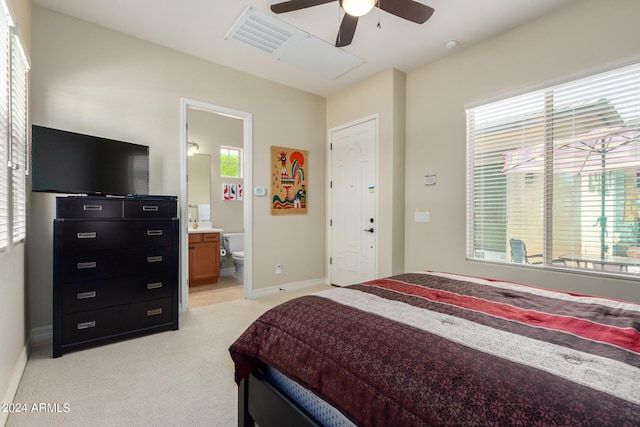 carpeted bedroom with connected bathroom, ceiling fan, and multiple windows