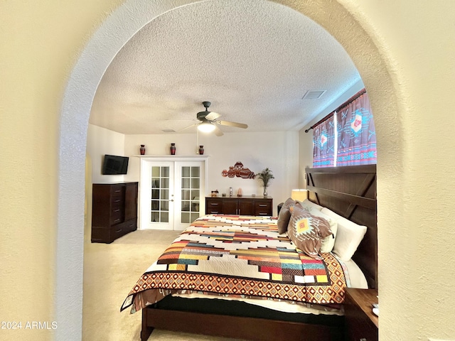 bedroom with ceiling fan, light colored carpet, french doors, and a textured ceiling