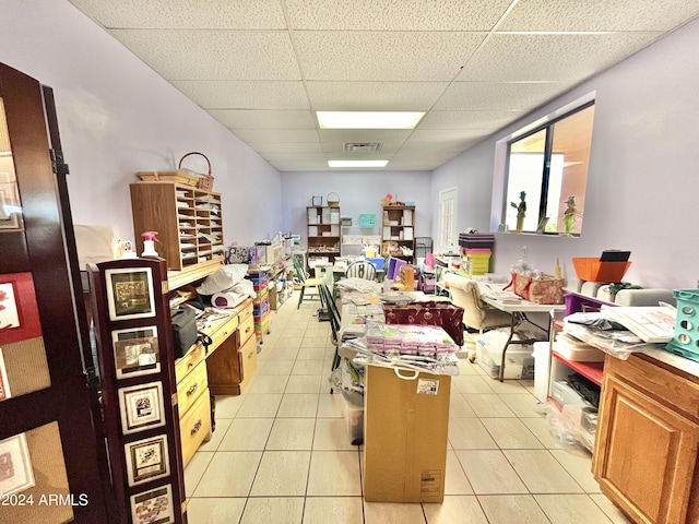 interior space with a drop ceiling and light tile patterned floors