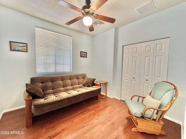 sitting room featuring ceiling fan, hardwood / wood-style floors, and a textured ceiling