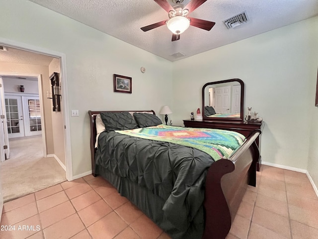 tiled bedroom featuring french doors, ceiling fan, and a textured ceiling