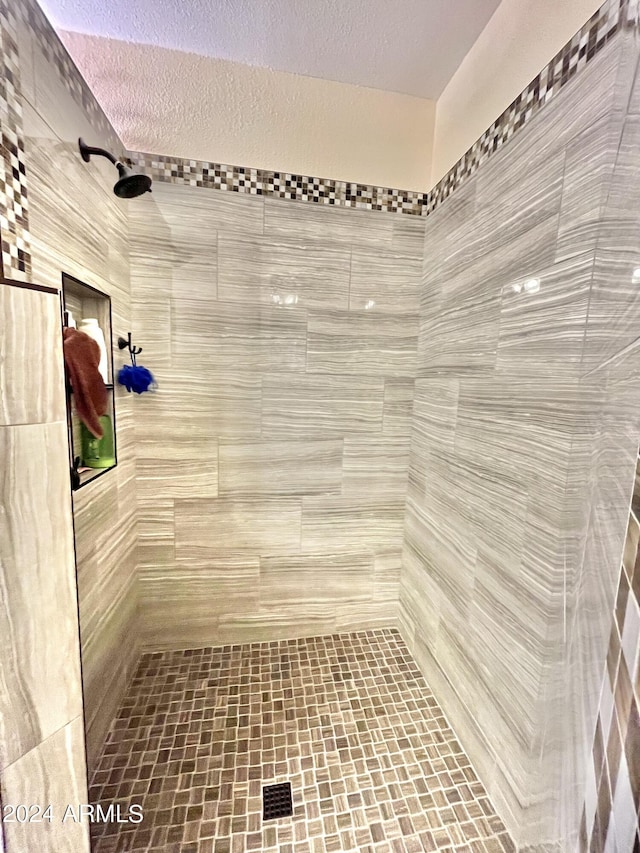 bathroom with a tile shower and a textured ceiling