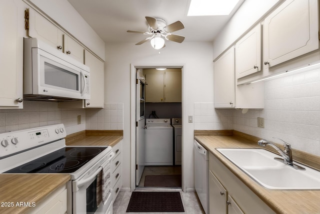 kitchen with a sink, decorative backsplash, white appliances, and washing machine and clothes dryer