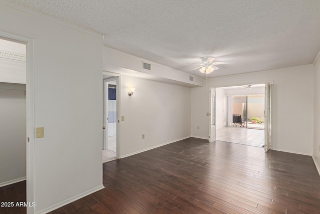 empty room featuring visible vents, a textured ceiling, wood finished floors, baseboards, and ceiling fan
