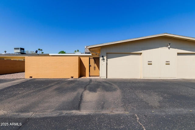 view of front of house featuring a garage, central AC unit, and fence
