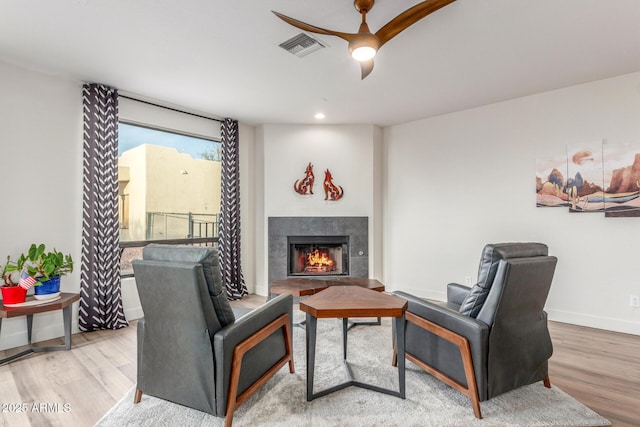 living room featuring hardwood / wood-style flooring, ceiling fan, and a fireplace