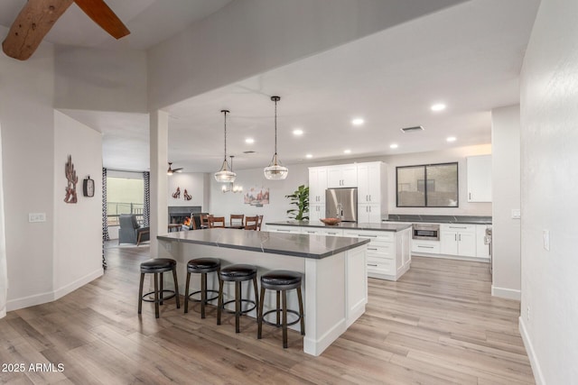 kitchen featuring pendant lighting, white cabinetry, stainless steel appliances, light hardwood / wood-style floors, and a kitchen island