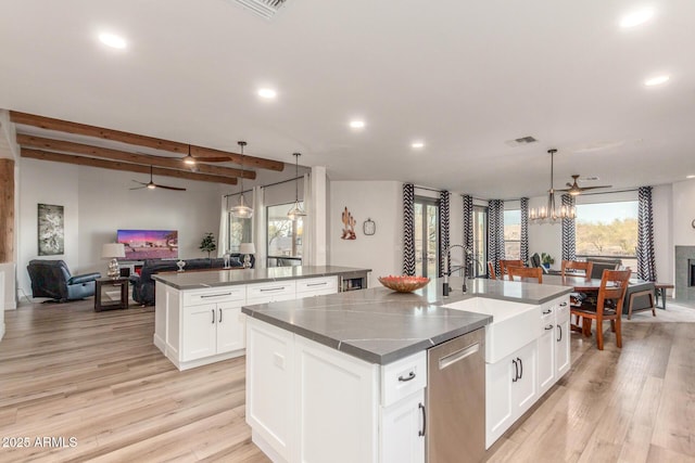 kitchen with white cabinetry, decorative light fixtures, and an island with sink