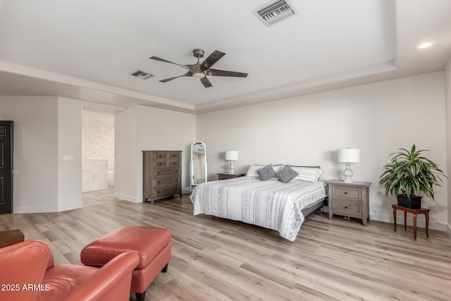 bedroom with light hardwood / wood-style flooring, a raised ceiling, and ceiling fan