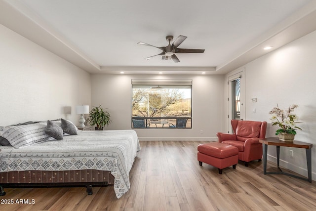 bedroom featuring hardwood / wood-style floors, a raised ceiling, and ceiling fan