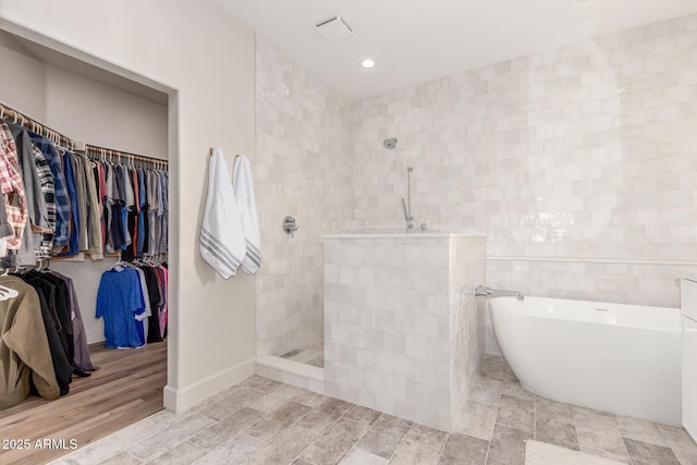 bathroom featuring tile walls, hardwood / wood-style floors, and plus walk in shower