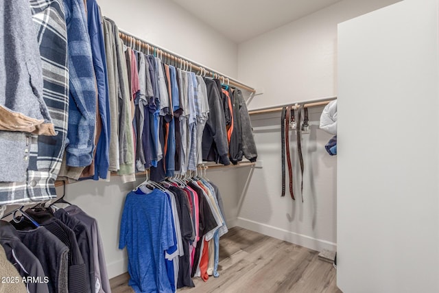 walk in closet with light hardwood / wood-style floors