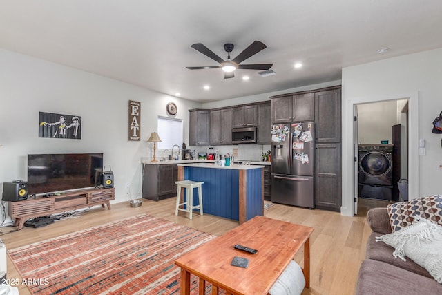 living room featuring ceiling fan, washer / dryer, and light hardwood / wood-style floors