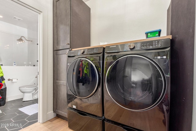 washroom with cabinets and washing machine and clothes dryer