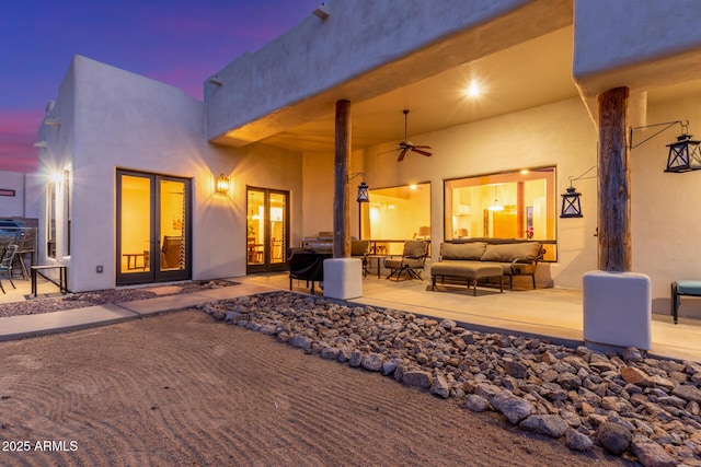 back house at dusk with an outdoor living space, a patio, ceiling fan, and french doors