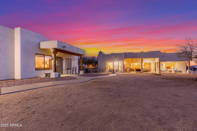 back house at dusk featuring a patio area