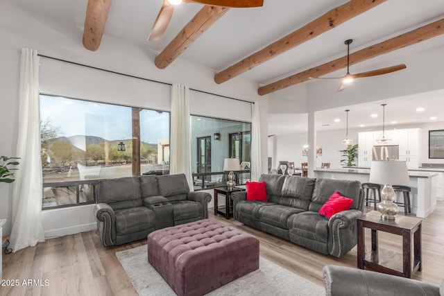 living room featuring a mountain view, beam ceiling, light hardwood / wood-style flooring, and ceiling fan