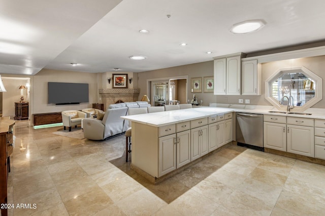 kitchen with kitchen peninsula, sink, stainless steel dishwasher, and a breakfast bar area