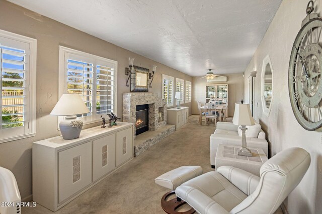 carpeted living room featuring ceiling fan, a textured ceiling, and a fireplace