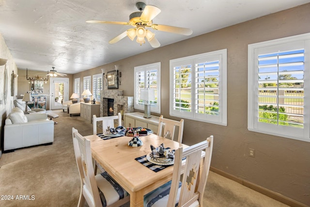 dining space featuring light colored carpet, ceiling fan, and a fireplace