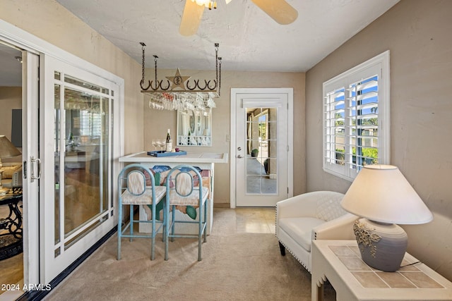 living area featuring ceiling fan, bar, and carpet flooring