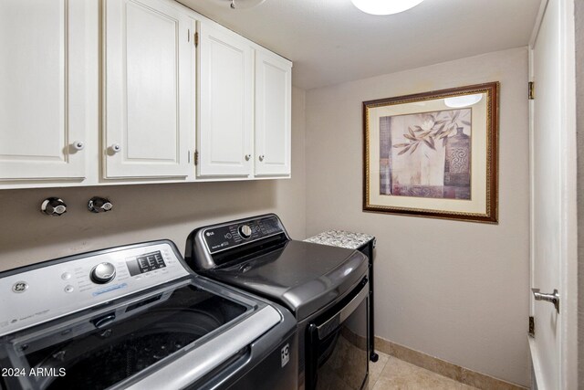 laundry room featuring light tile patterned floors, separate washer and dryer, and cabinets