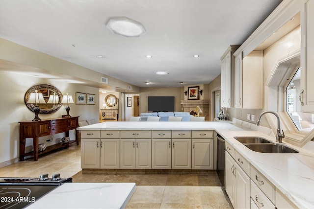 kitchen with light stone countertops, sink, kitchen peninsula, and dishwasher