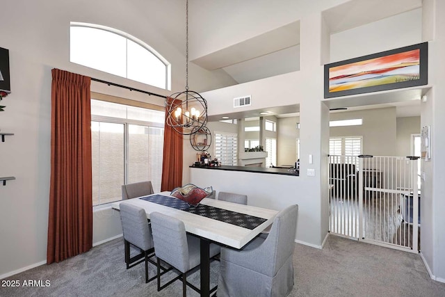 carpeted dining space featuring baseboards, a high ceiling, and visible vents