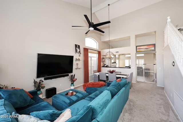 carpeted living room featuring high vaulted ceiling, visible vents, baseboards, and ceiling fan with notable chandelier