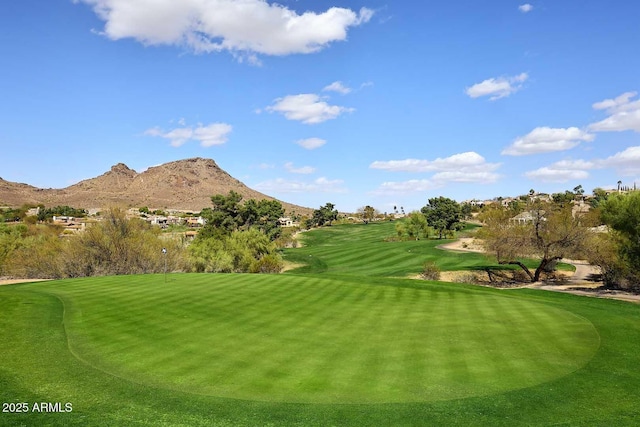 view of property's community with a mountain view, golf course view, and a lawn