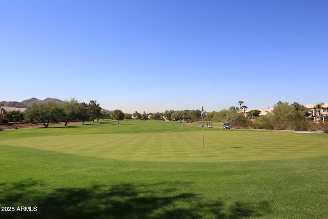 view of property's community with view of golf course and a yard