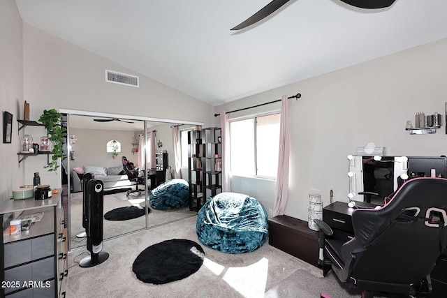 carpeted office featuring vaulted ceiling, visible vents, and a ceiling fan