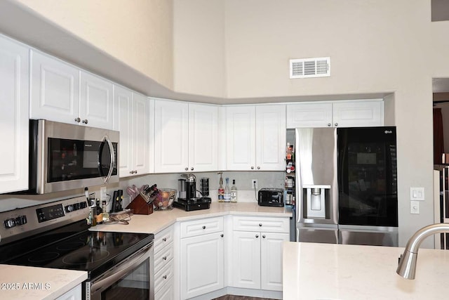 kitchen with white cabinets, visible vents, appliances with stainless steel finishes, and light countertops