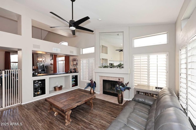 living room with a fireplace, high vaulted ceiling, wood finished floors, and ceiling fan with notable chandelier