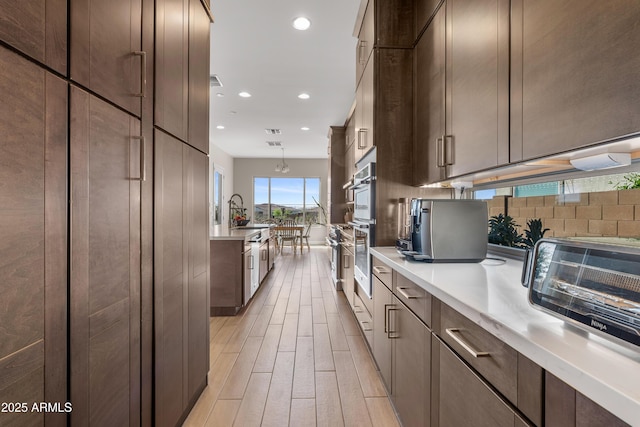 kitchen with light wood-type flooring, a sink, backsplash, recessed lighting, and light countertops