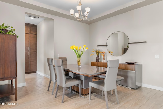 dining space with a notable chandelier, light wood-type flooring, and baseboards