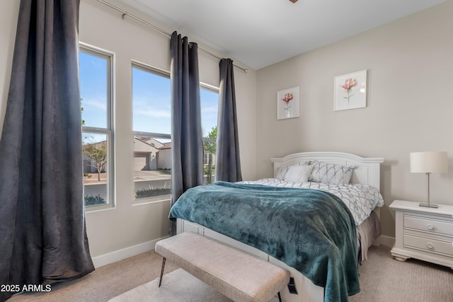 bedroom featuring multiple windows, light carpet, and baseboards