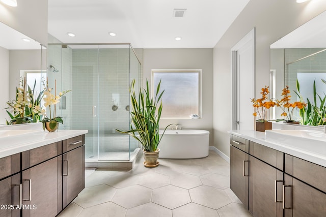 full bathroom featuring visible vents, two vanities, a freestanding bath, a sink, and a shower stall