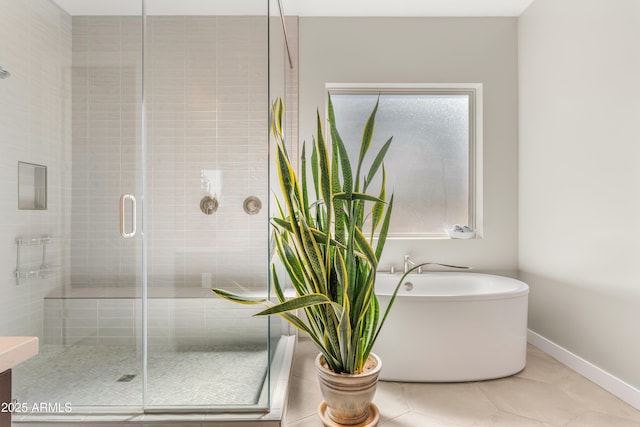 full bathroom featuring tile patterned flooring, a shower stall, a freestanding tub, and baseboards