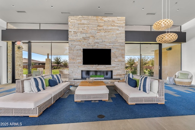 living area with plenty of natural light, visible vents, and an outdoor stone fireplace