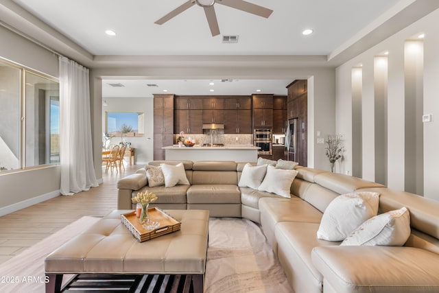 living room with light wood finished floors, visible vents, recessed lighting, and baseboards