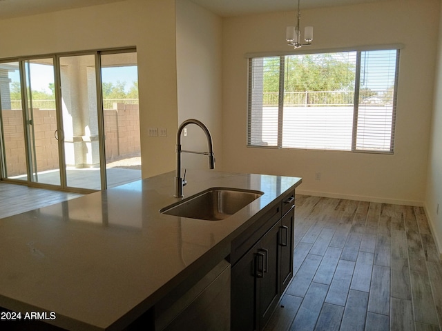 kitchen with a wealth of natural light, an island with sink, hanging light fixtures, and light hardwood / wood-style flooring