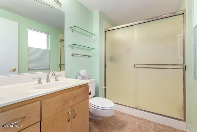 bathroom featuring toilet, tile patterned flooring, vanity, and walk in shower