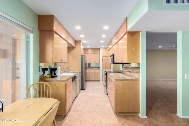 kitchen featuring sink, light stone counters, light brown cabinetry, light tile patterned flooring, and appliances with stainless steel finishes