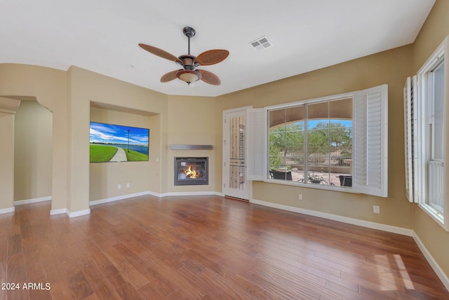 unfurnished living room with hardwood / wood-style floors, a wealth of natural light, and ceiling fan