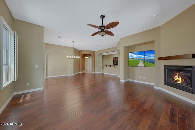 unfurnished living room with ceiling fan with notable chandelier and hardwood / wood-style floors