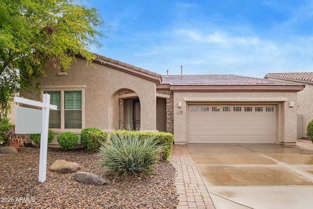 view of front facade with a garage, a tiled roof, concrete driveway, and stucco siding