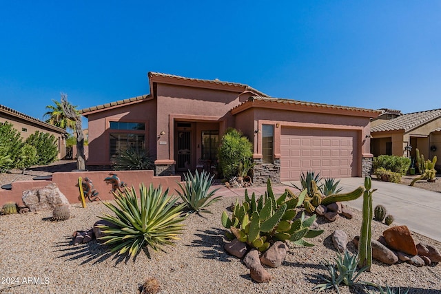 mediterranean / spanish home with driveway, stone siding, a tiled roof, an attached garage, and stucco siding