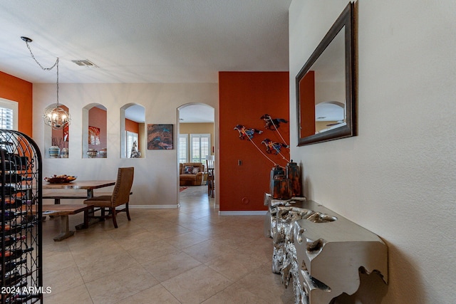 interior space featuring visible vents, baseboards, arched walkways, an inviting chandelier, and light tile patterned flooring