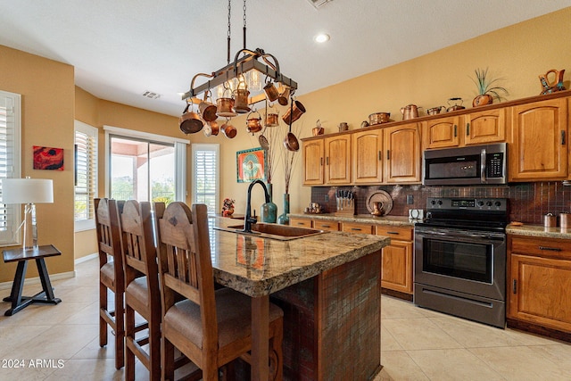 kitchen featuring appliances with stainless steel finishes, a breakfast bar, a sink, and decorative backsplash